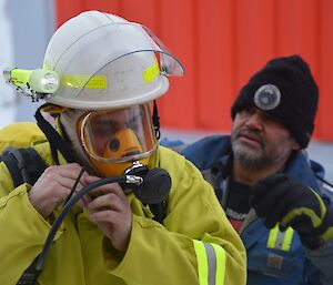 Expeditioner assisting a colleague dressed in fire fighting equipment
