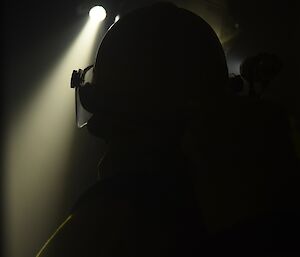 Expeditioner’s fire helmet silhouetted by the light from a torch