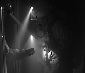 Two expeditioners in BA equipment in a dark corridor inspect a marker they have found