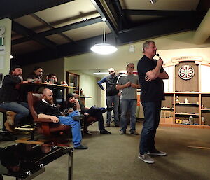 Expeditioners seated beside a bar watching the darts match