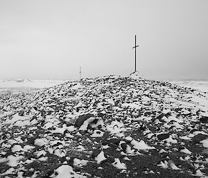 Two crosses stand on a ridgeline above rock and snow
