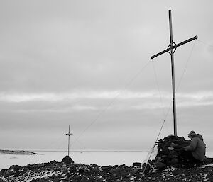 Expeditioner crouching beside one of the crosses with another in the background