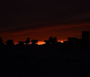 Vehicles parked on the helipad silhouetted at dawn