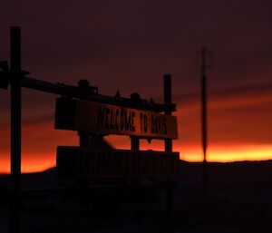 A welcome to Davis sign illuminated in the foreground of a predawn sky