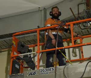 Expeditioner smiling from atop a scissor lift.