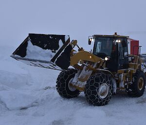 Mechanical digger transporting snow off station.
