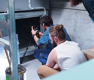 Expeditioner kneeling in front of some duct work.