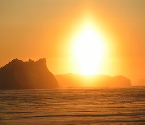 Sun shining across large icebergs stuck fast in the sea ice.