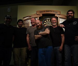 Six expeditioners from the Davis darts team smile at the camera after their victory.