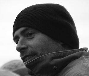 Close-up profile image of an expeditioner in a beanie and coat collar up to his chin.