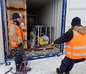 Two expeditioners pulling a pallet out of a container.