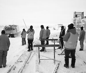 The crowd observe a Hägglunds tracked vehicle steering around canes.