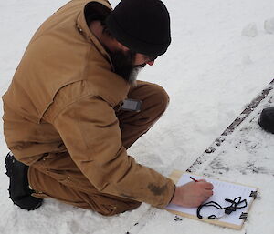 Expeditioner kneeling beside a list of the Hägglunds slalom participants.