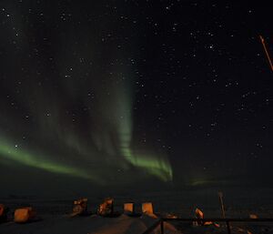 Green aurora shining in a starlit sky above the station buildings.