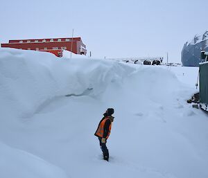 Expeditioner standing at the bottom of a large wave-shaped snow feature.
