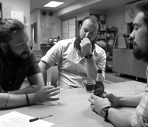 Three expeditioners seated around a table during the quiz, deep in thought.