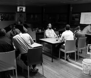 Expeditioners seated in teams of four for a quiz night.