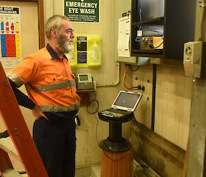 Expeditioner standing beside a computer and satellite link hardware