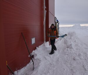 Expeditioner shovelling snow at the entrance of a drive way