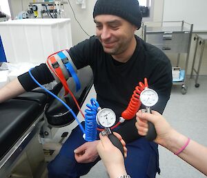 Expeditioner kneeling beside a surgical table wearing an operative tourniquet