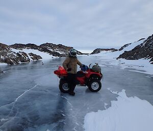 Expeditioner posing beside his quad bike on a frozen lake