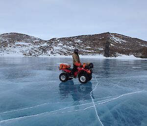 Expeditioner riding his quad bike across a frozen lake