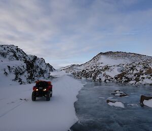 A quad bike parked up on the left hand side of a frozen lake