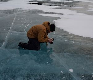 Expeditioner kneeling on sea ice taking photos