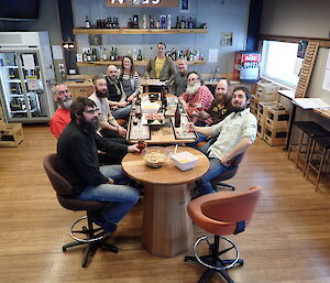 Group of expeditioners sitting around the bar smiling at camera