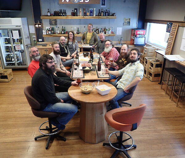 Group of expeditioners sitting around the bar smiling at camera