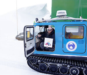 Expeditioner seated in tracked vehicle holds up the illustrated sign