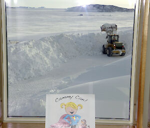 Illustration propped up against a window in the background a bulldozer moving snow