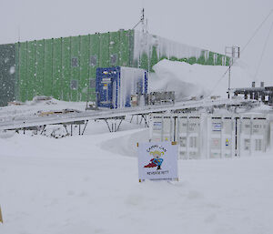 Illustration partially buried in the snow with services building in the background