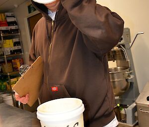 Expeditioner standing with a lid blocking his face in the kitchen