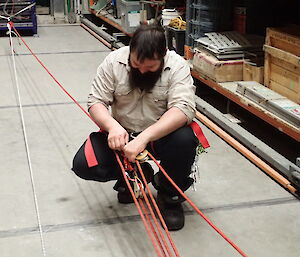 Expeditioner kneeling in an aisle beside a rope pulley system