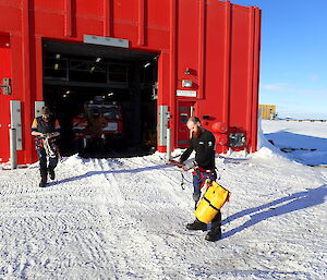 Four expeditioners stand in front of a red tracked vehicle carrying ropes and harnesses