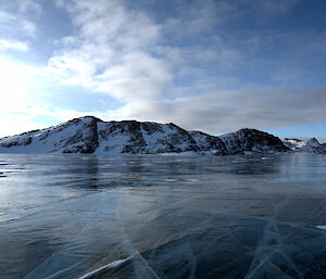 A frozen lake with snow covered mountains in the background