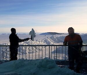 Two expeditioners shovelling snow off a balcony