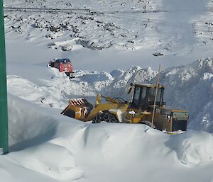 Mechanical digger half concealed by a snow bank