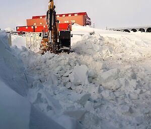 Excavator clearing snow in background with large build up of snow in foreground