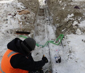 Expeditioner kneeling over exposed pipe work