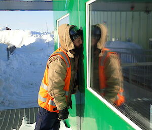 Expeditioner with face pressed against green wall of living quarters