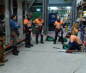 Expeditioners standing in an aisle look on as another expeditioner demonstrates technical rope skills