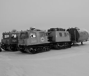 Two hagglund tracked vehicles parked beside one another on frozen white surface