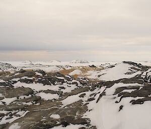 Rocky terrain in foreground with islands encased in sea ice in background