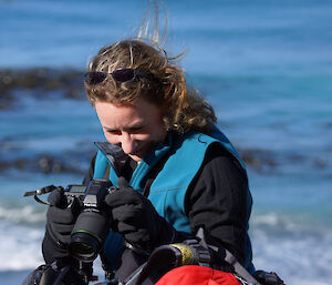 Expeditioner in foreground with head down smiling with sea in background