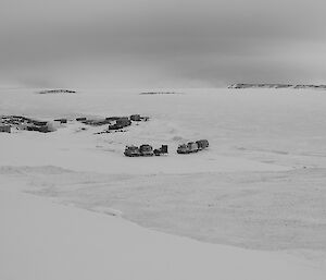 Two tracked vehicles driving in convoy cross the tide crack from the sea ice onto snow covered land. Sea ice background