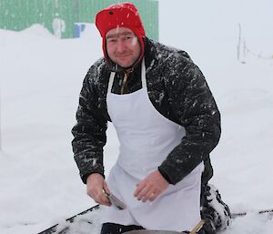 Expeditioner kneeling on a mat in the snow