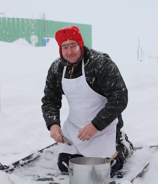 Expeditioner kneeling on a mat in the snow