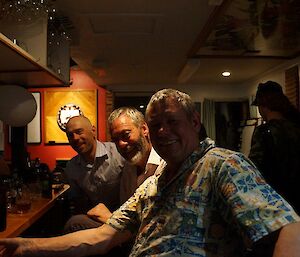 Three expeditioners sitting at a bar facing camera
